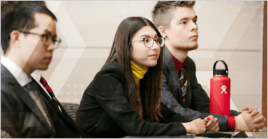 Three students are looking at the person who gives speech