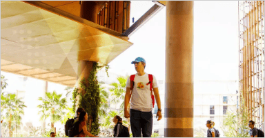 A person is walking under the building, and other people are walking to the other side