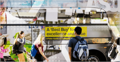 A bus with many stickers while students are walking pass by it