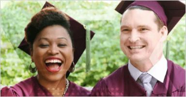 Two people are smiling while wearing graduate hats